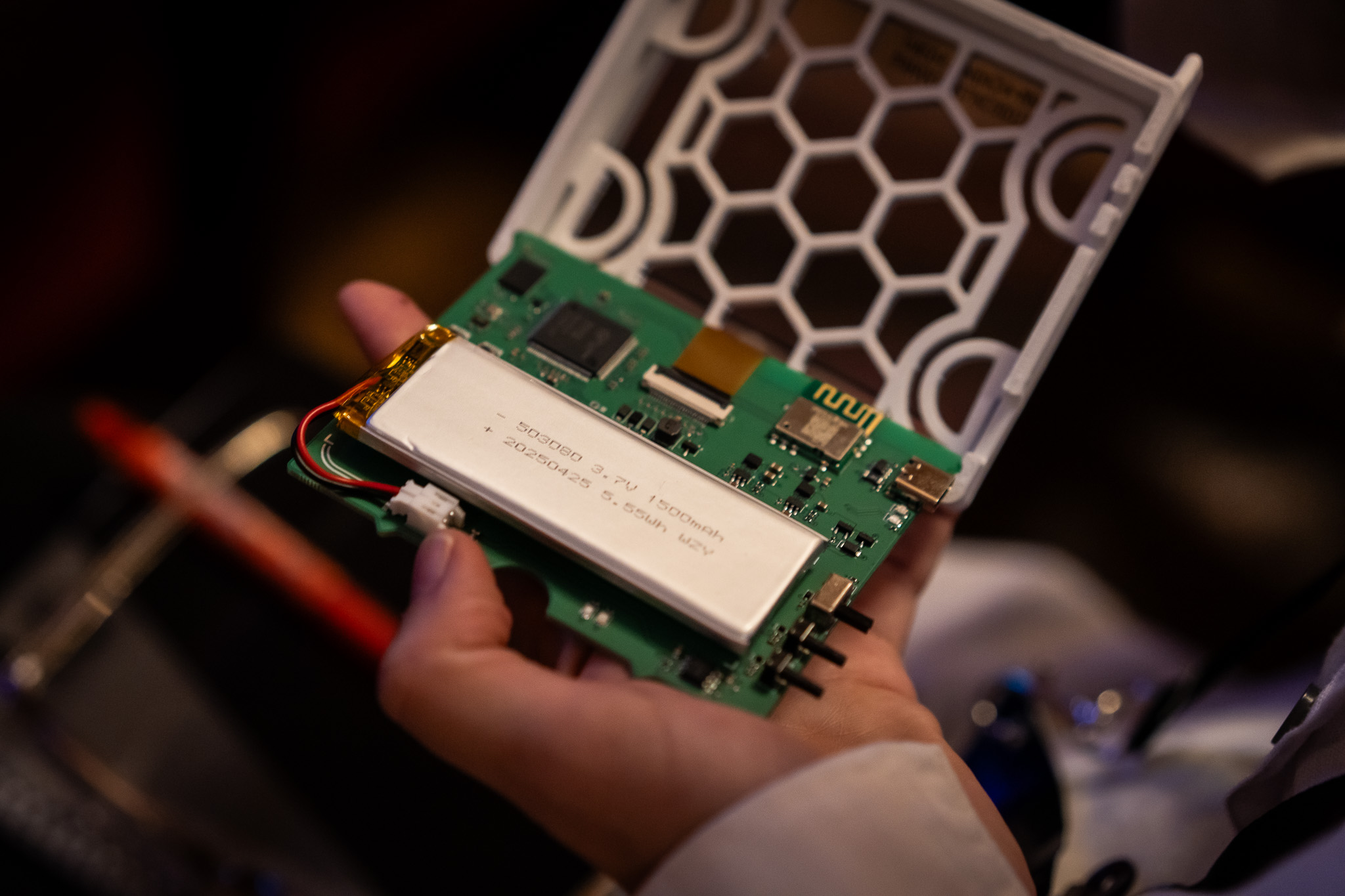 eInk name badge device opened showing battery and circuit board.